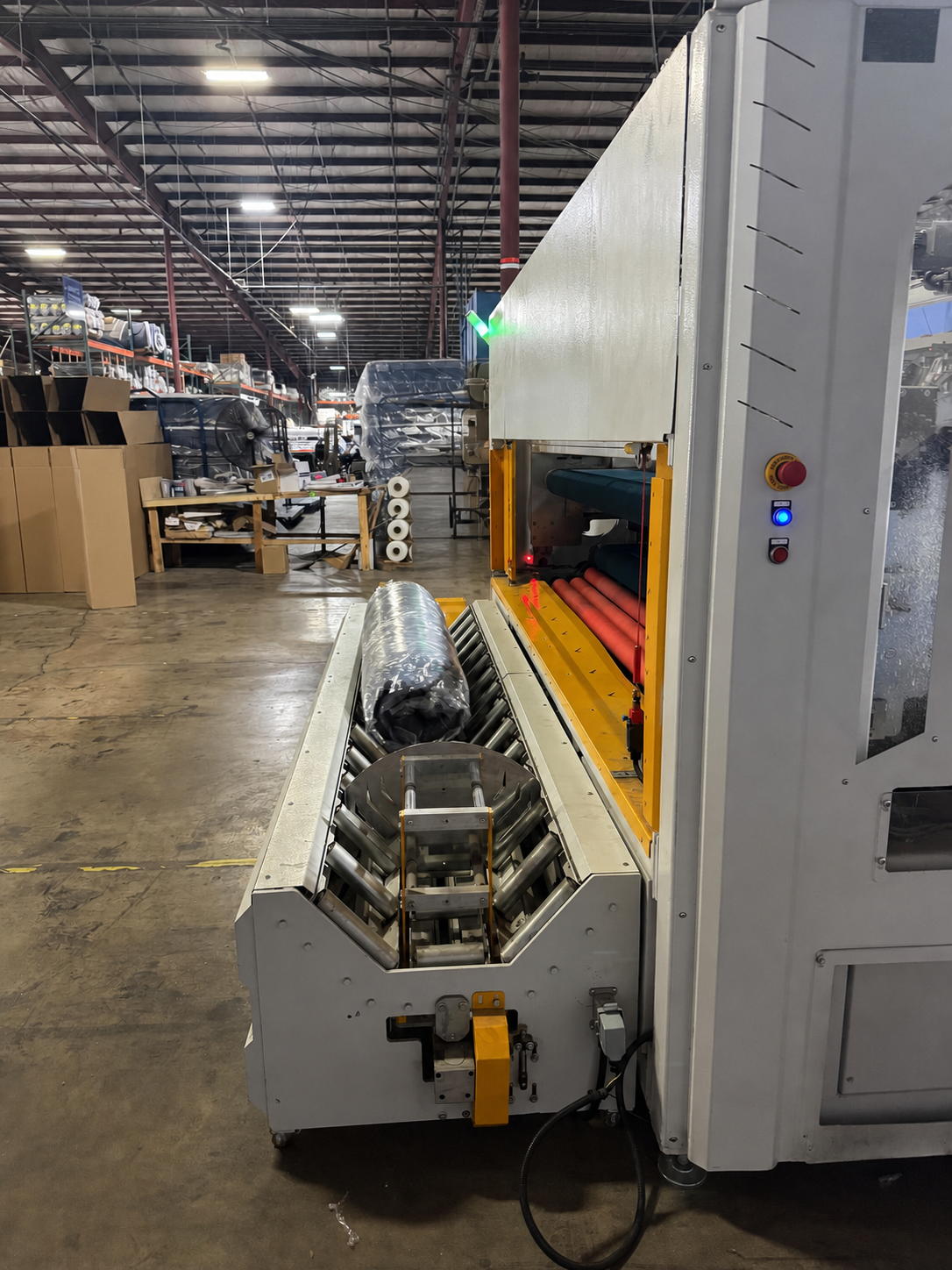 A compressed and rolled unbranded mattress leaving the boxing machine